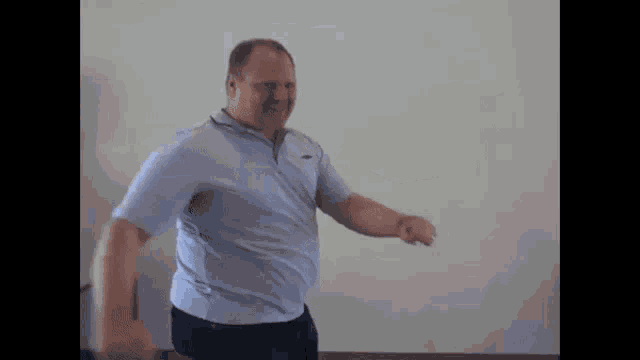 a man is dancing in front of a white wall .