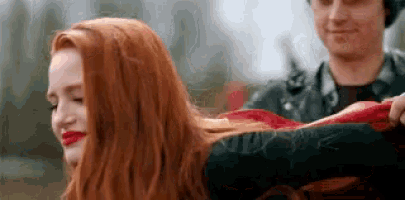 a woman with red hair is standing next to a man in a leather jacket .