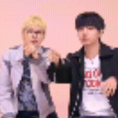 a couple of men are standing next to each other and making a peace sign .