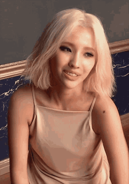 a woman with blonde hair wearing a tan dress