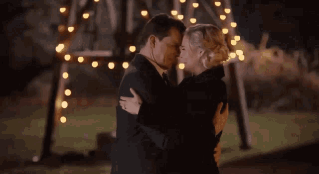 a man and a woman are dancing in front of a christmas tree .