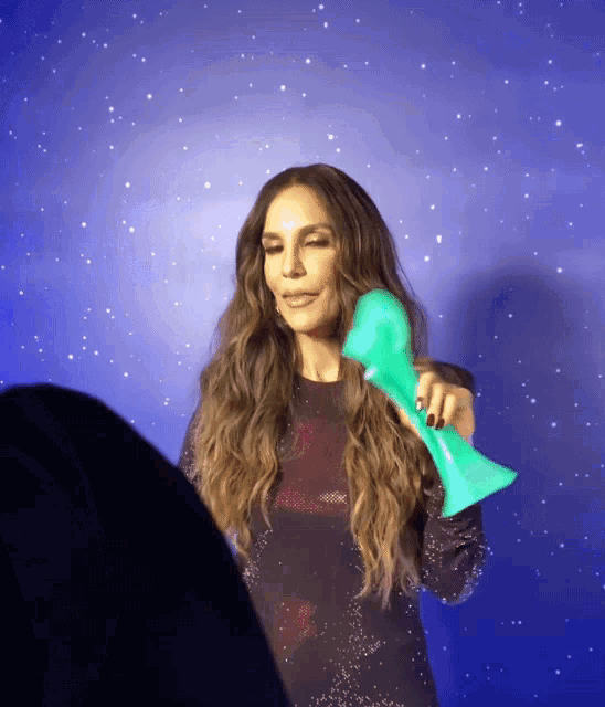 a woman is holding a green object in front of a blue background