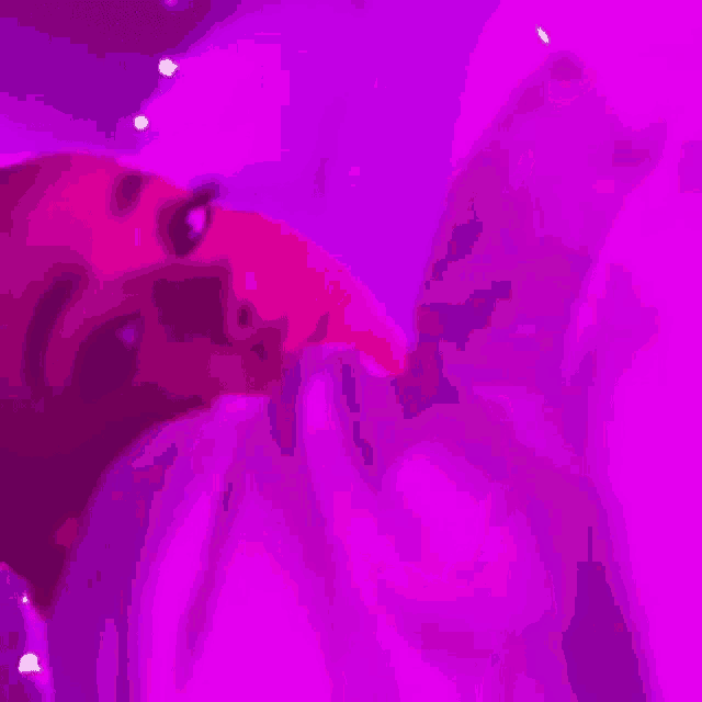 a woman is laying on a bed under a purple light and looking at the camera .