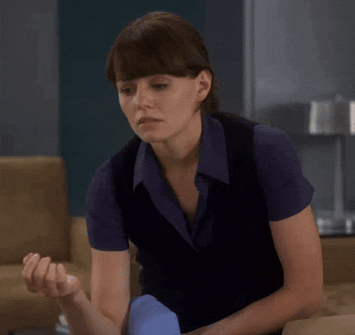 a woman in a blue shirt is sitting on a chair