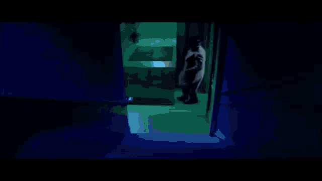 a man in a suit and tie is standing in the dark looking up .