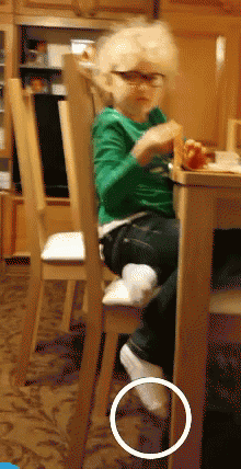 a little boy sits at a table with a circle around his foot