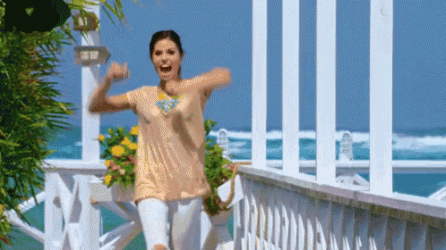a woman is standing on a balcony overlooking the ocean with her arms outstretched .