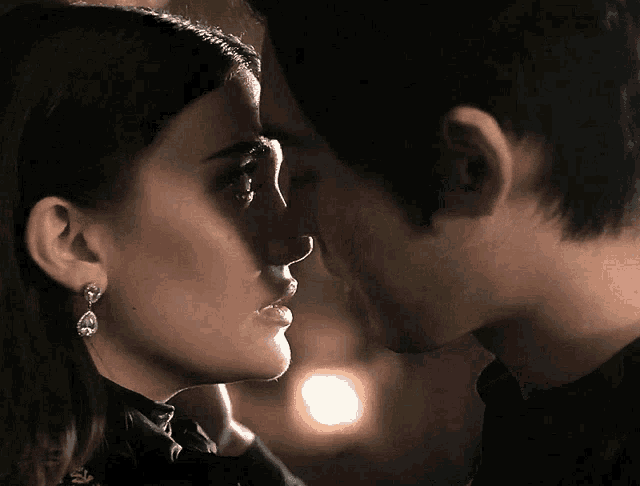 a man and a woman are kissing and the woman has earrings on