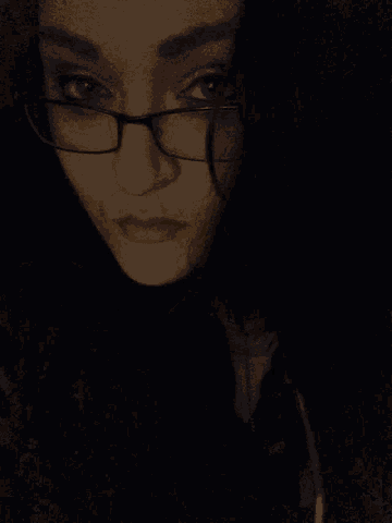 a close up of a woman wearing glasses with her eyes closed