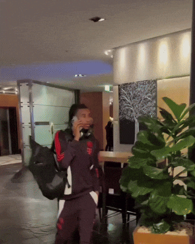 a man talking on a cell phone while carrying a black bag