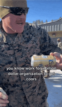 a man in a us marines uniform holds a can of coors