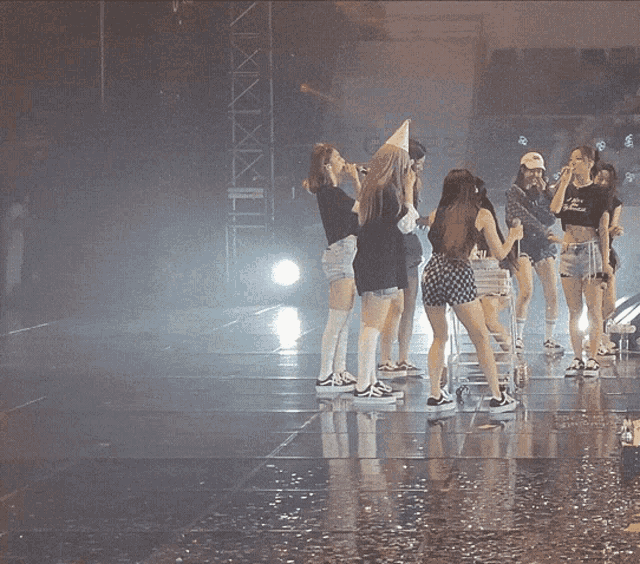 a group of women are standing on a wet stage and one of them is wearing a black shirt that says ' a '