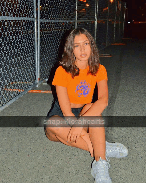 a girl sits on the ground in front of a chain link fence with the caption snap kierahearts