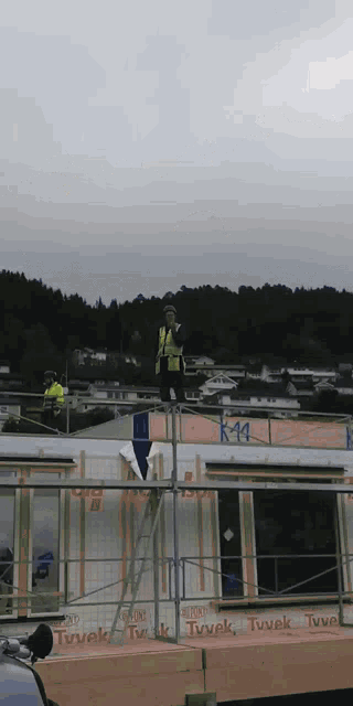 a man stands on a scaffolding on top of a building that says tuvek on it