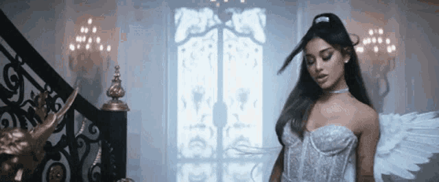 a woman in a white dress with angel wings is standing next to a staircase