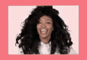 a woman with long black curly hair is smiling and wearing a white shirt .