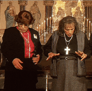 a man and a woman are standing next to each other with a cross necklace