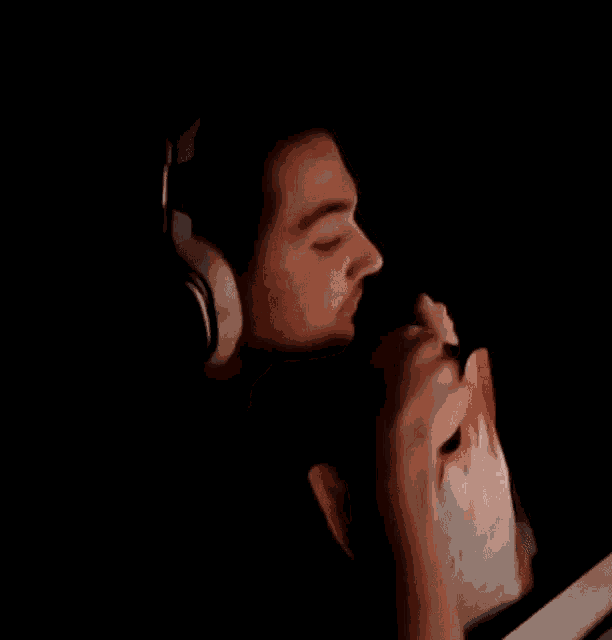 a man wearing headphones is sitting in front of a computer screen in a dark room .