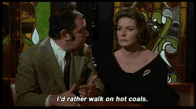a man and a woman are sitting at a table and the man says i 'd rather walk on hot coals