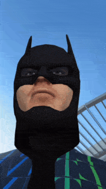 a man in a batman mask looks at the camera with a blue sky in the background