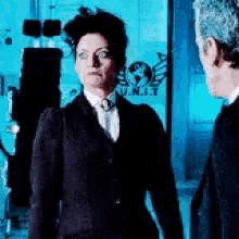 a woman in a suit and tie is standing next to a man in a suit