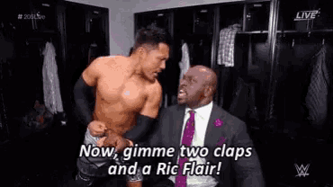 a shirtless wrestler is talking to a man in a suit and tie .
