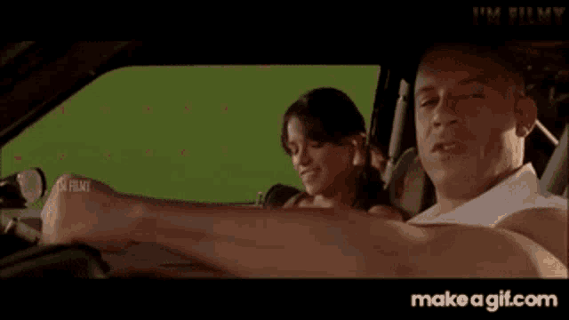 a man and a woman are sitting in a car with a green screen behind them