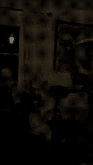 a man is holding a glass of wine in the dark