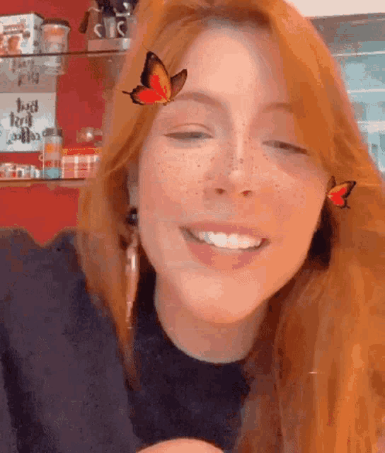 a woman with red hair and freckles is smiling with a butterfly on her face .