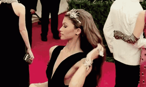 a woman in a black dress is standing on a red carpet .