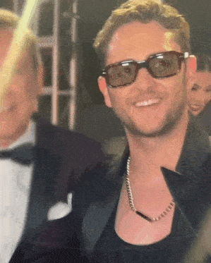 a close up of a man wearing sunglasses and a chain around his neck