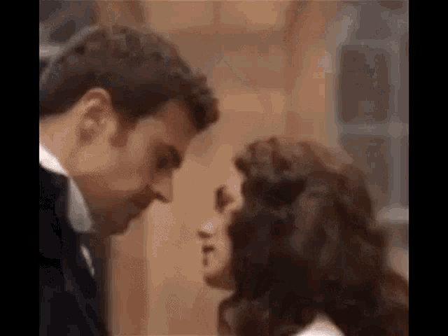 a man and a woman are looking at each other and kissing .
