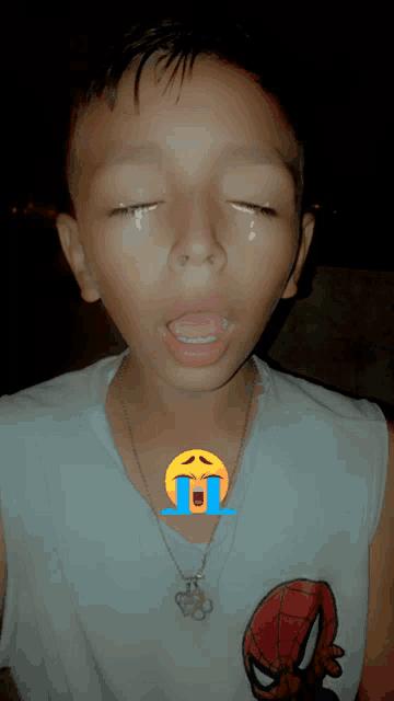 a young boy wearing a spiderman shirt is crying with a tear coming out of his eye