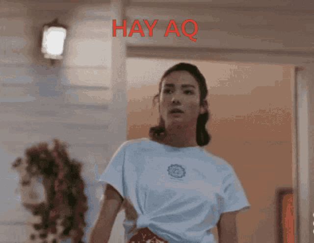 a woman wearing a white shirt with hay aq written on the top