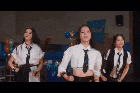 three girls in school uniforms and ties are dancing on a stage