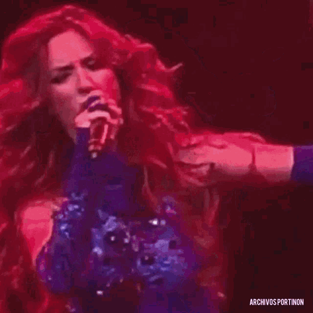 a woman in a blue dress is singing into a microphone on stage .