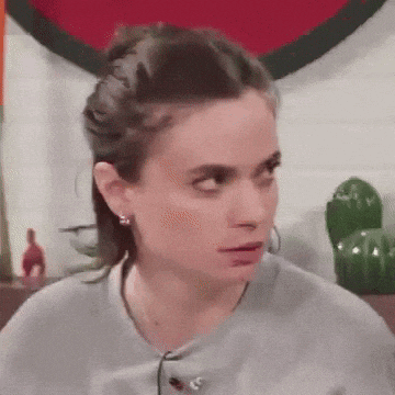 a woman wearing a gray sweater and earrings looks at the camera