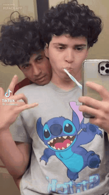 a man in a stitch shirt is brushing his teeth while another man looks on