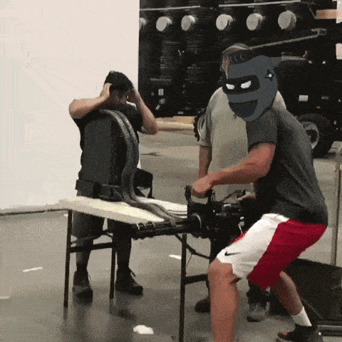 a man with a mask on his head is standing next to a table