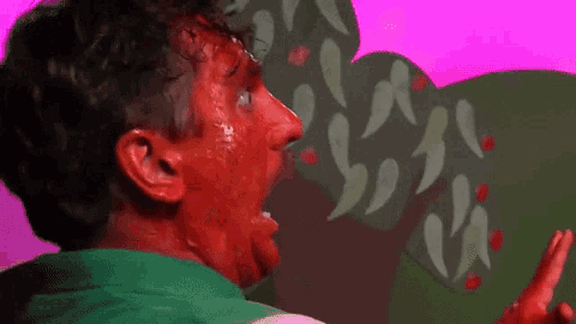 a man with red paint on his face is pointing at a cactus .