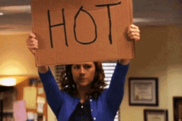 a woman is holding a cardboard sign that says hot over her head .