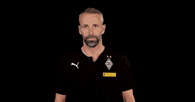 a man with a beard is wearing a black shirt with a puma logo on the front