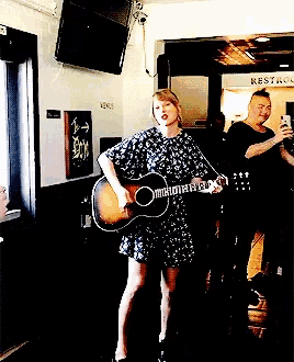 a woman singing into a microphone while playing a guitar