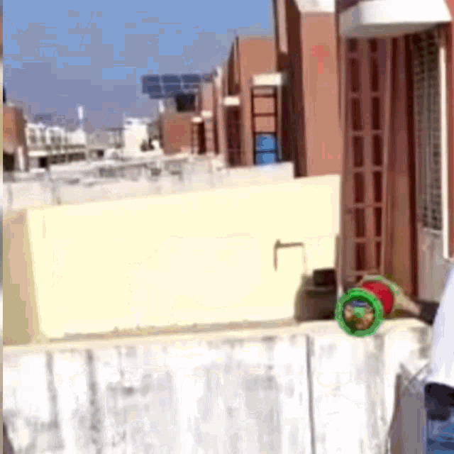 a person is playing with a toy on a balcony with a brick building in the background