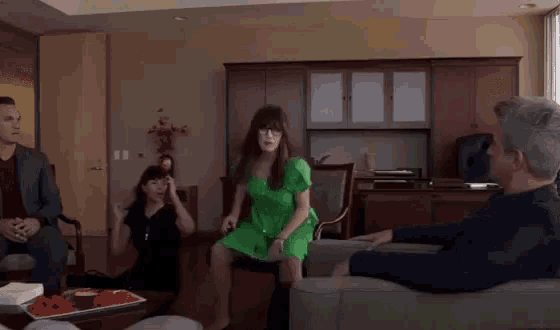 a woman in a green dress is dancing in a room
