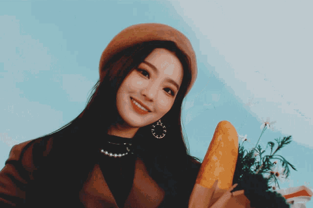 a woman in a hat holds a bunch of carrots