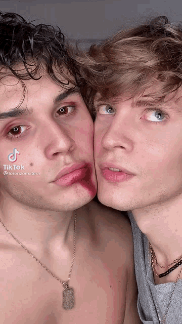 two young men are standing next to each other and one has blood on his face and the other has a necklace around his neck