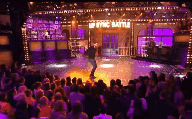 a man is performing on stage in front of a crowd with a sign that says lp sync battle