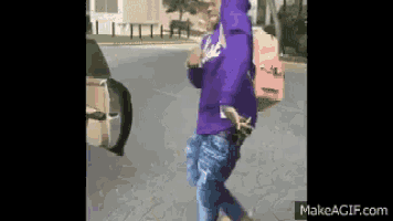 a person wearing a purple hoodie and jeans is walking down the street .