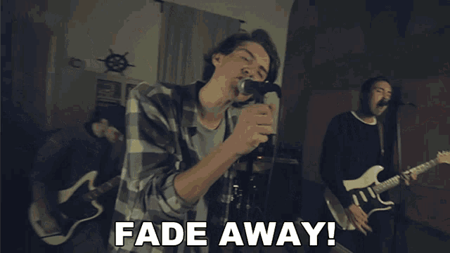 a man singing into a microphone while another man plays a guitar with the words fade away below him